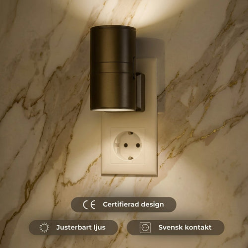 Luma LED-vägglampa i svart inkopplad i vägguttag på marmorsvägg
